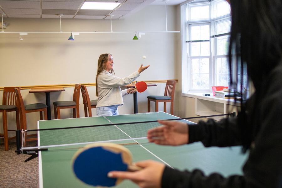 Young women playing ping pong in a common area of the suites.